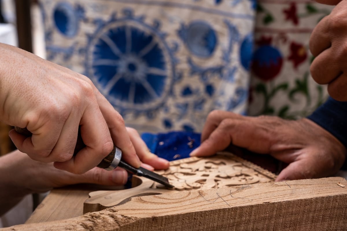 a woman and a man carving a small piece of wood