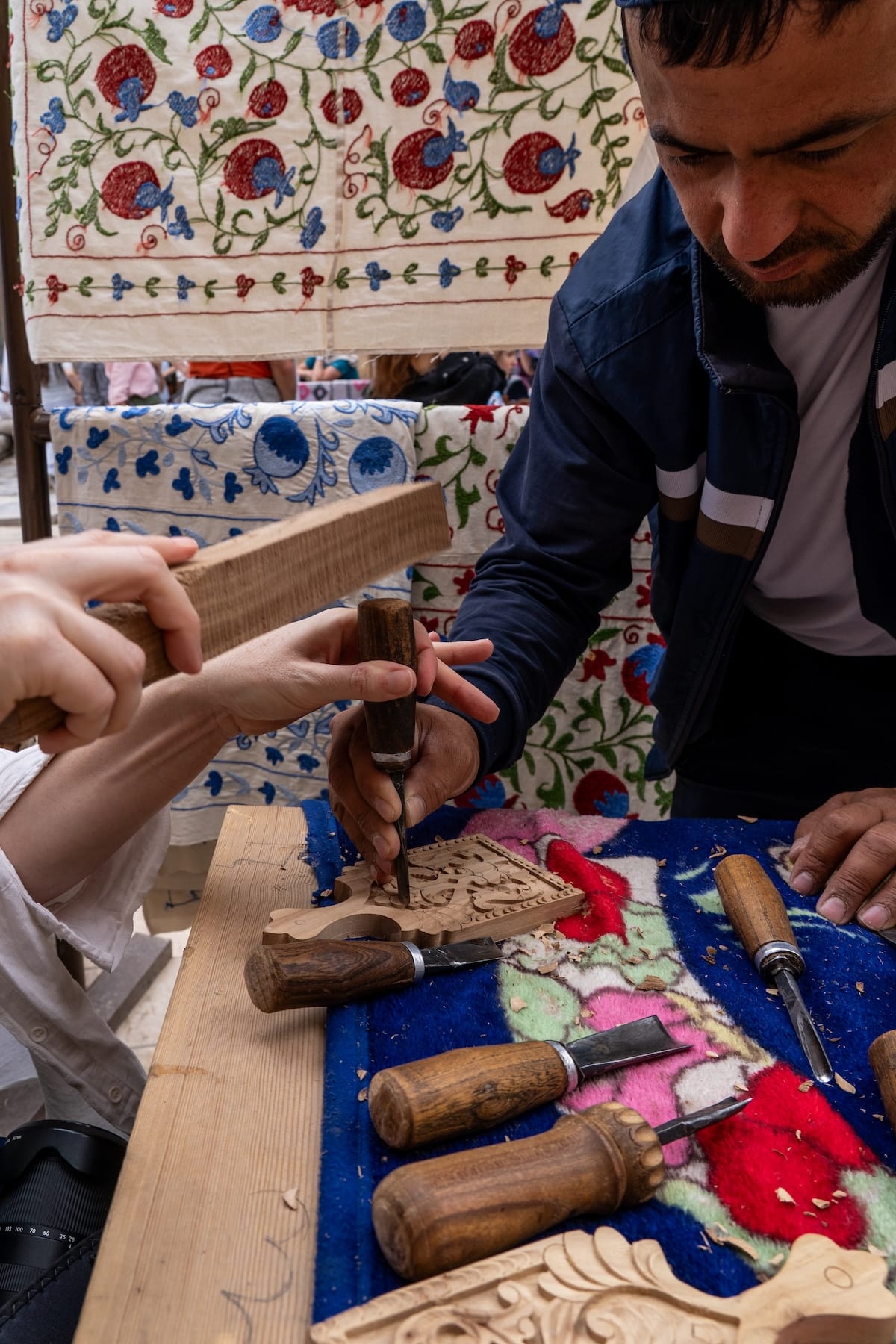 a woman and man chiseling a piece of wood on a messy table
