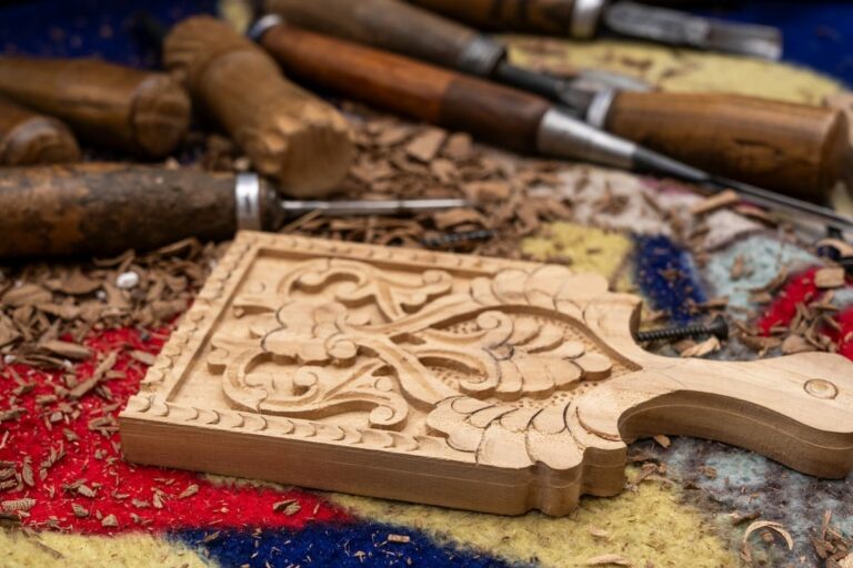 a wooden, carved small cutting board on a messy table