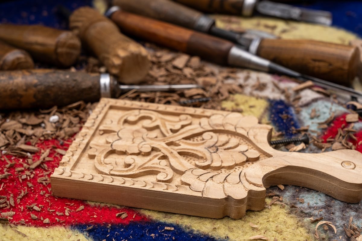 a wooden, carved small cutting board on a messy table