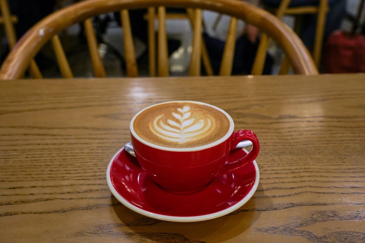 a flat white in a red cup on a table