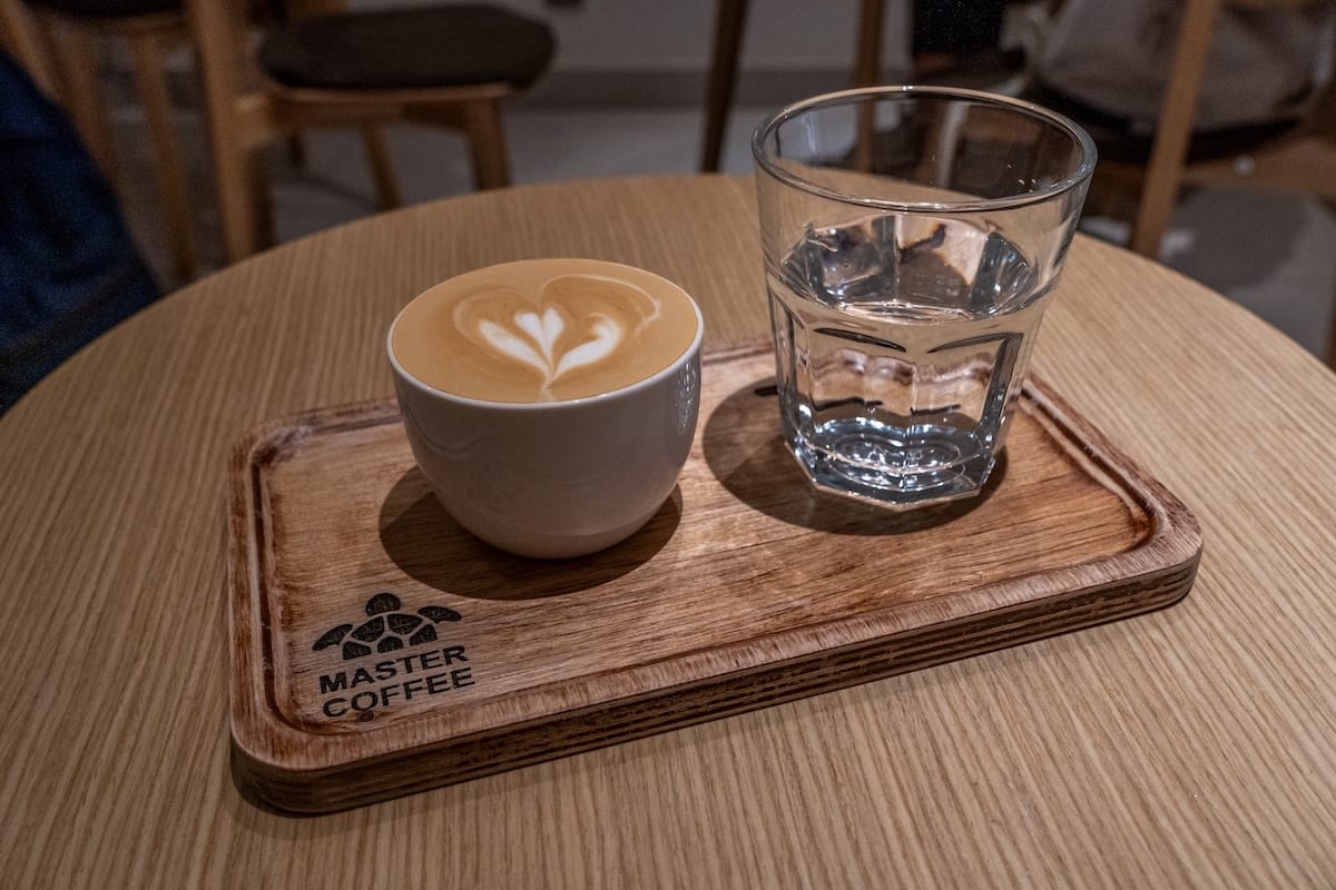 a flat white and a water on a table in a cafe
