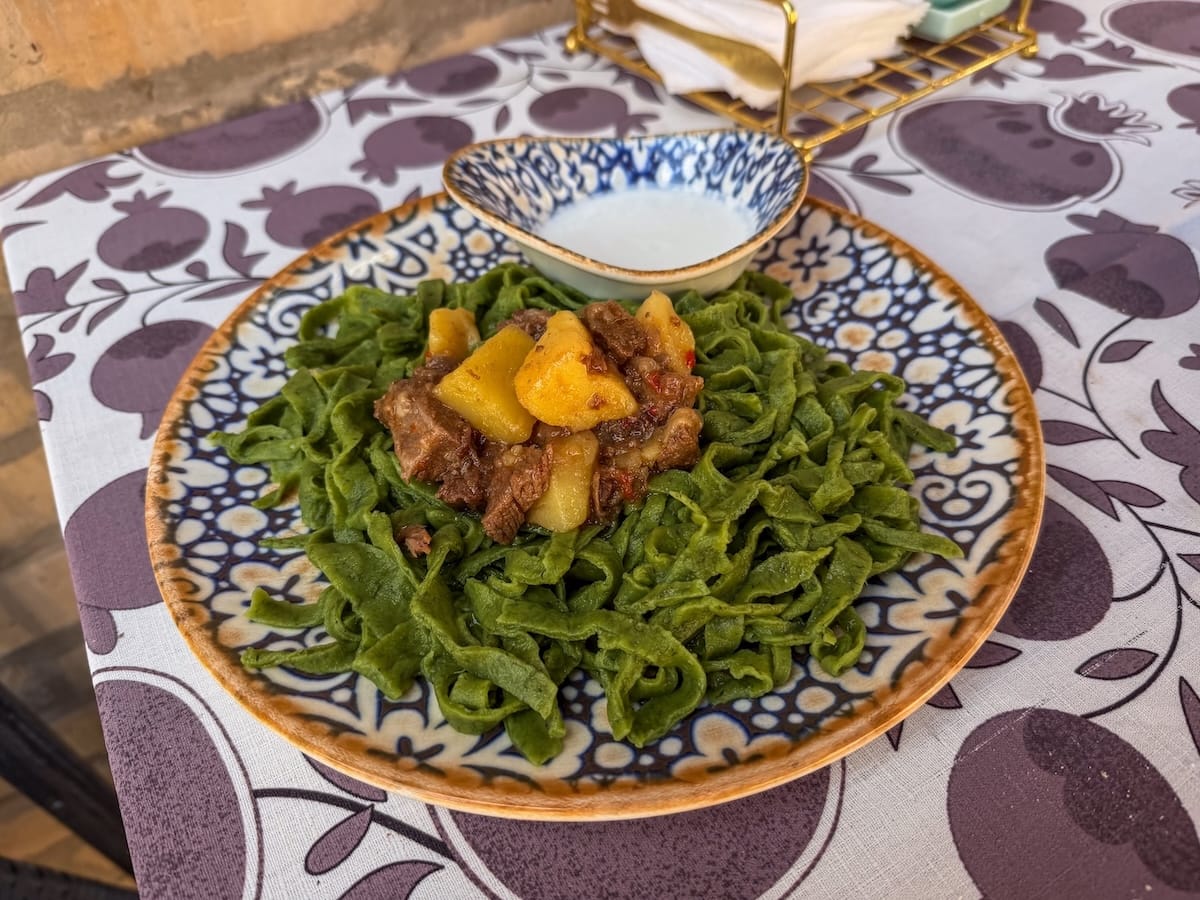 a plate of green dill noodles on a table with a white sauce