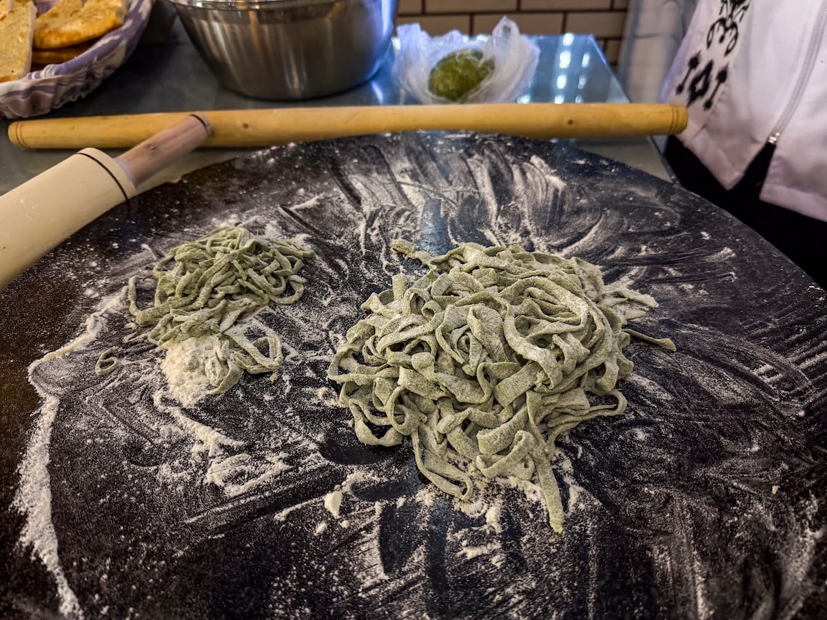 green noodles on a table that have been freshly cut and covered in flour