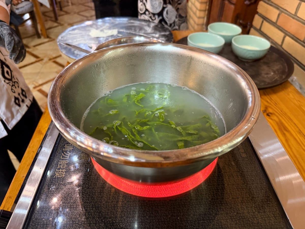 a bowl of green dill noodles on a burner