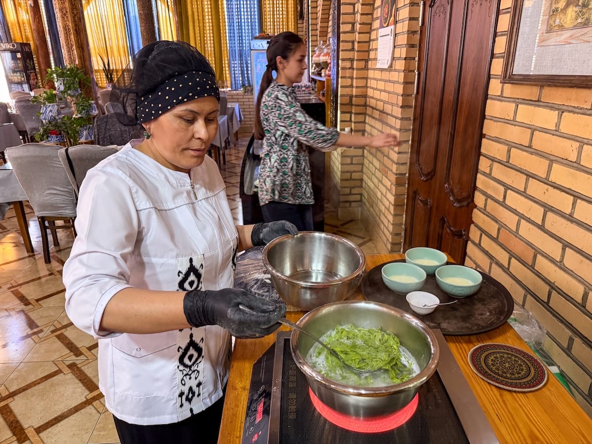 Learning to make shivit osh in Khiva, Uzbekistan
a woman chef making a green noodle dish on a burner in a restaurant