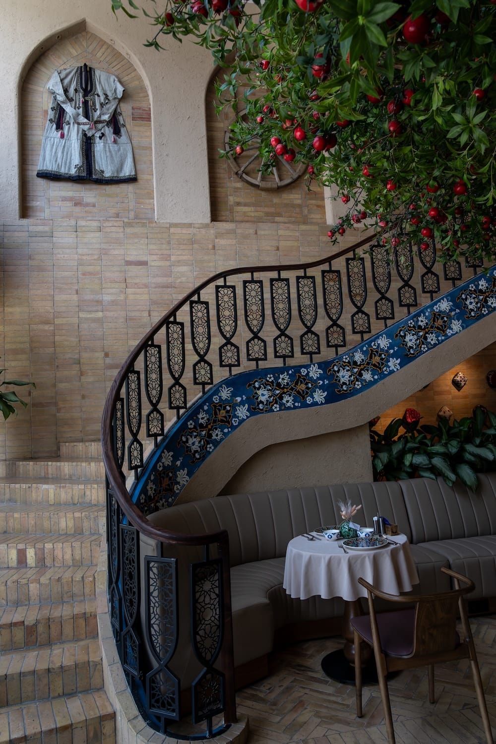 a restaurant with a gorgeous staircase and a fake pomegranate tree in it