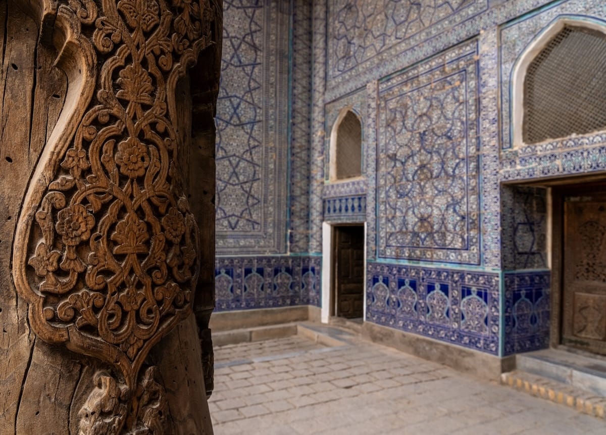 a photo of a wooden carved pillar with tiled walls behind it