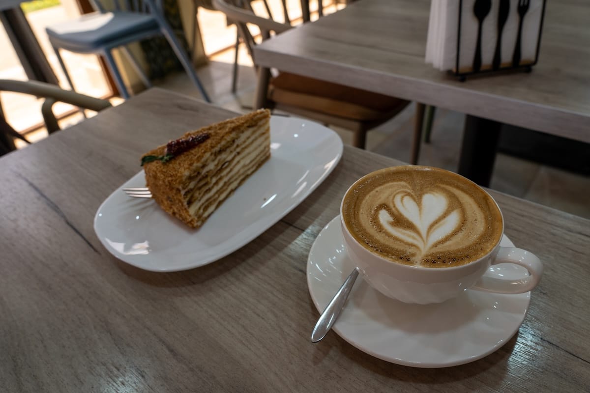 a coffee with latte art and a honey cake on a table in a coffee shop