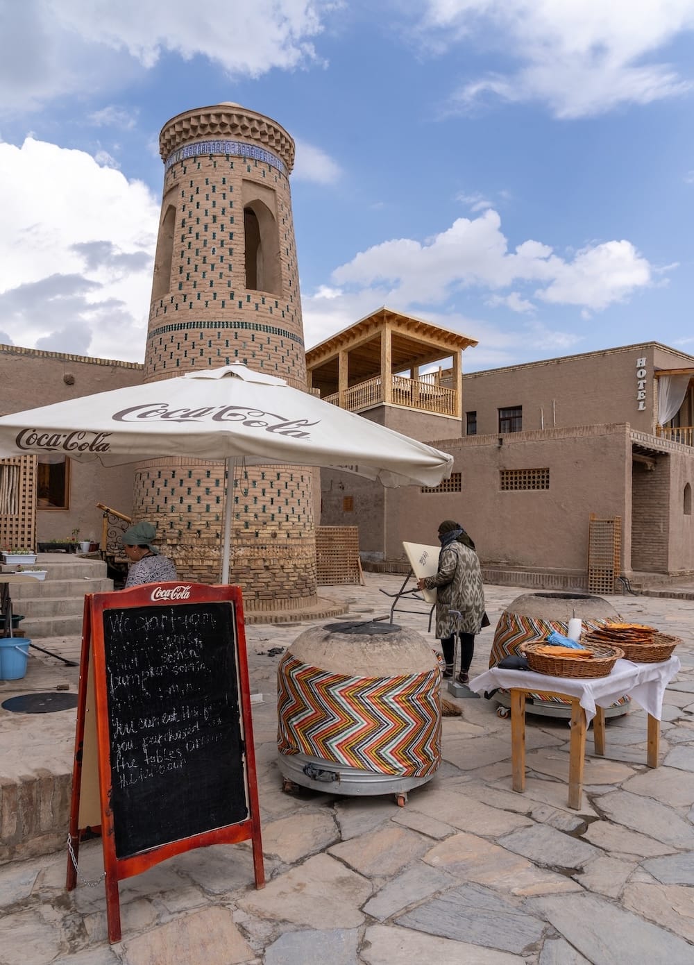 an outdoor tandir with a minaret behind it