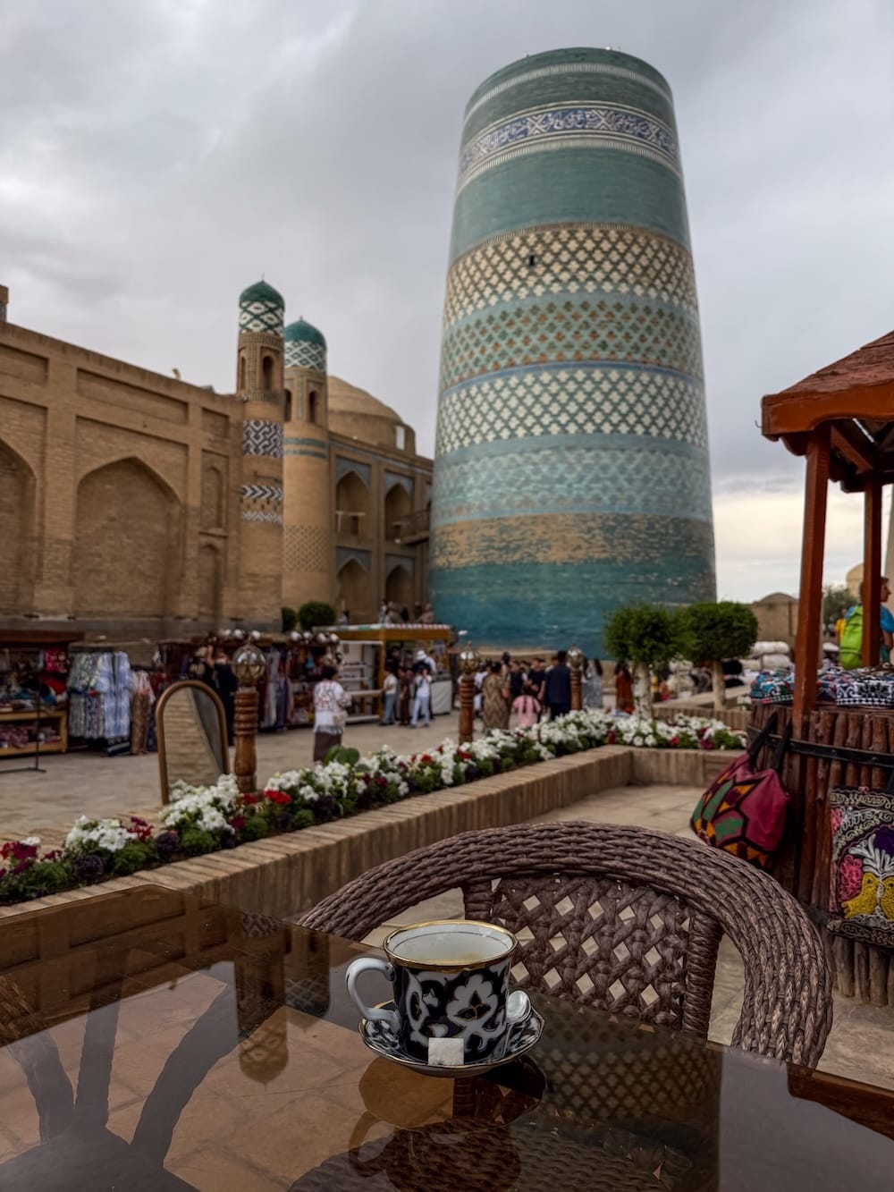a coffee on a table overlooking a tiled minaret in uzbekistan