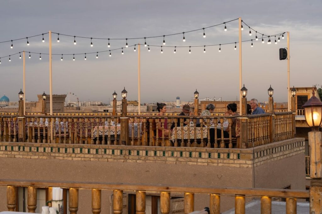 a tan colored terrace of a restaurant with people sitting on it best restaurants in khiva, uzbekistan