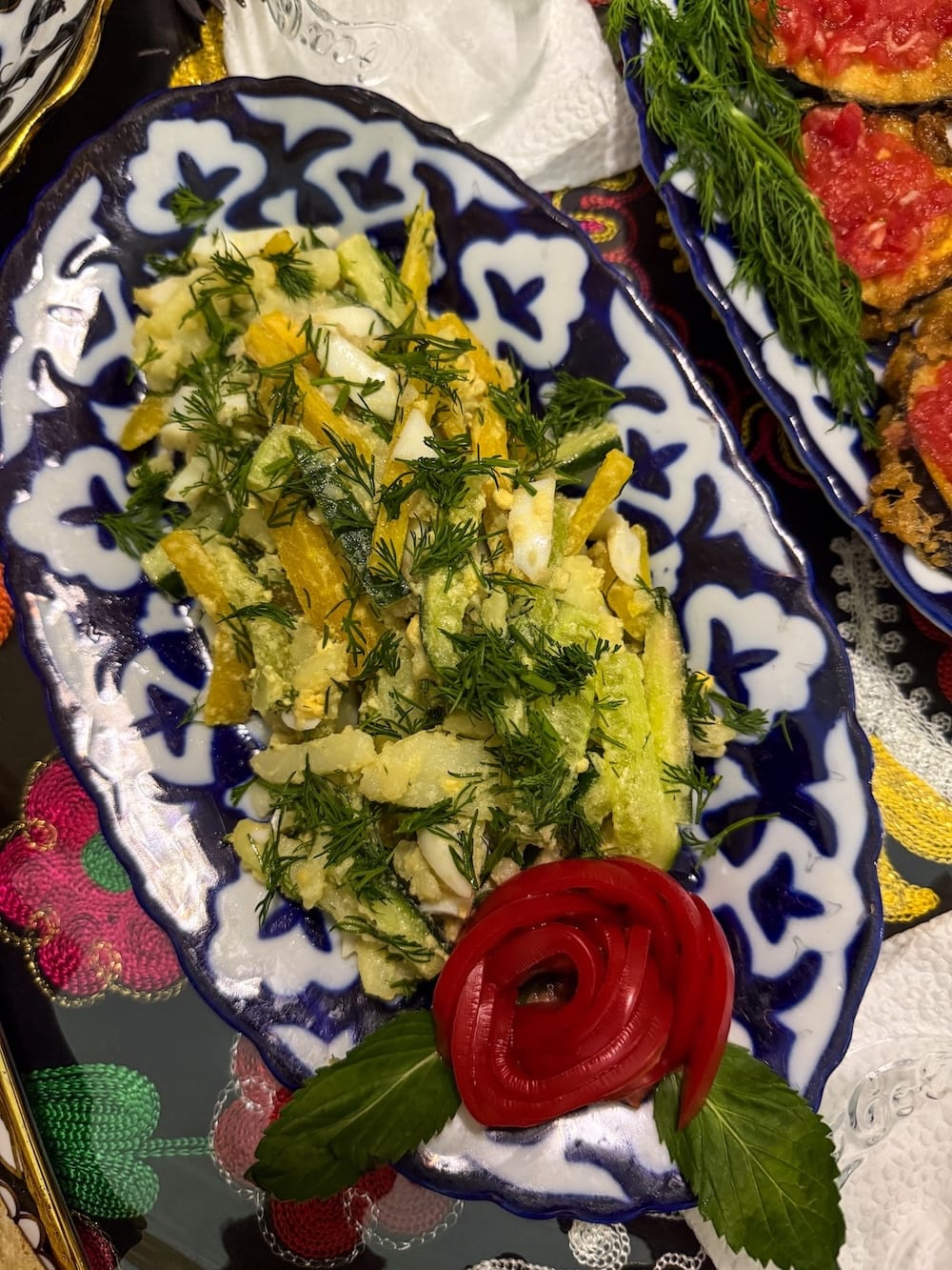 a traditional uzbek plate with a salad on it covered in dill