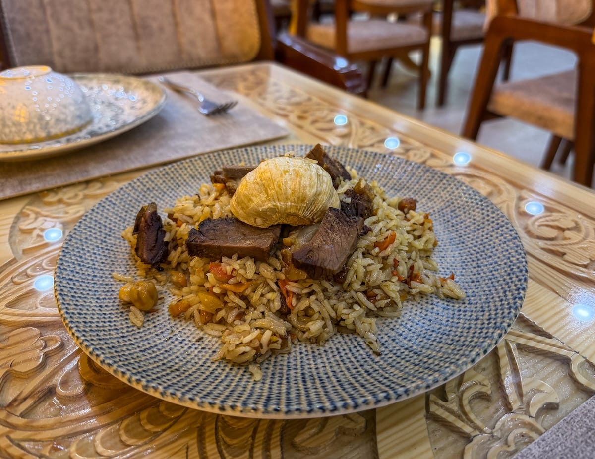 a plate of plov with meat and garlic on top in uzbekistan