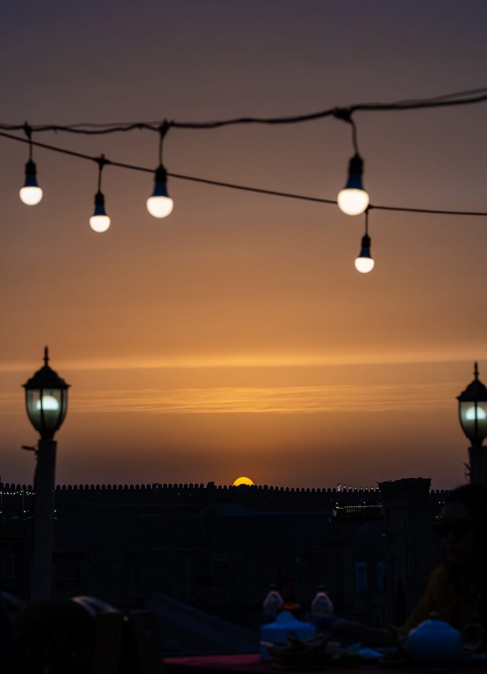 a view of a sunset in uzbekistan with a string of lights in the photo