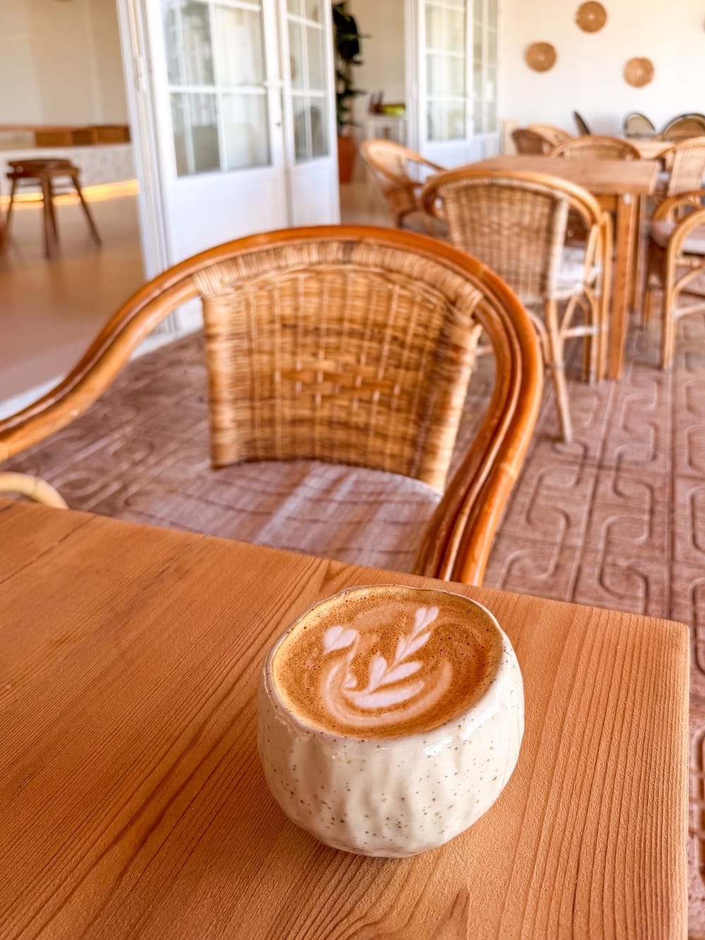 a flat white in a ceramic cup on a wooden table