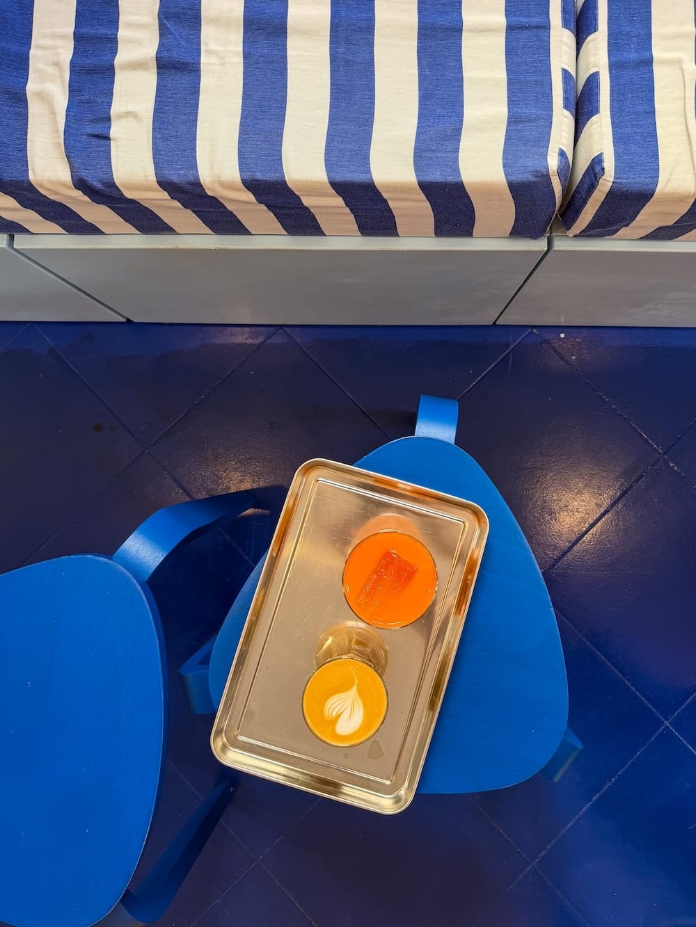 Tasty coffee in Ciutadella at Bubu's Corner
A bright blue floor and bench with a coffee and orange juice on a tray on top of it.