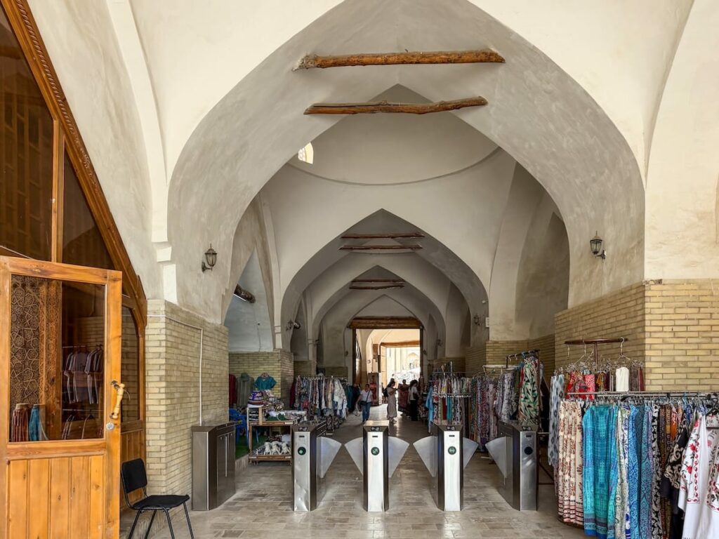 an entrance with turnstiles with a lot of clothing and merchandise on racks