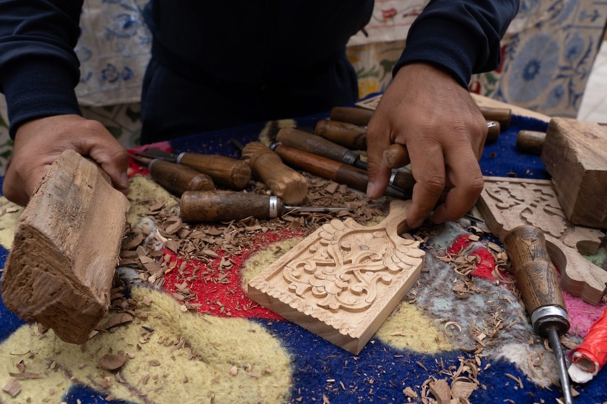 a man's hands with wooden cutting boards freshly carved on a table