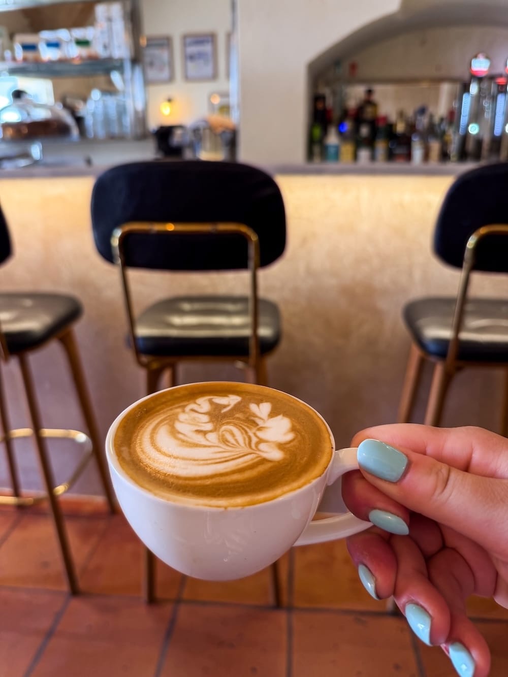 A flat white at La Reina Specialty Coffee
A woman's hand holding a white cup with a flat white coffee in it