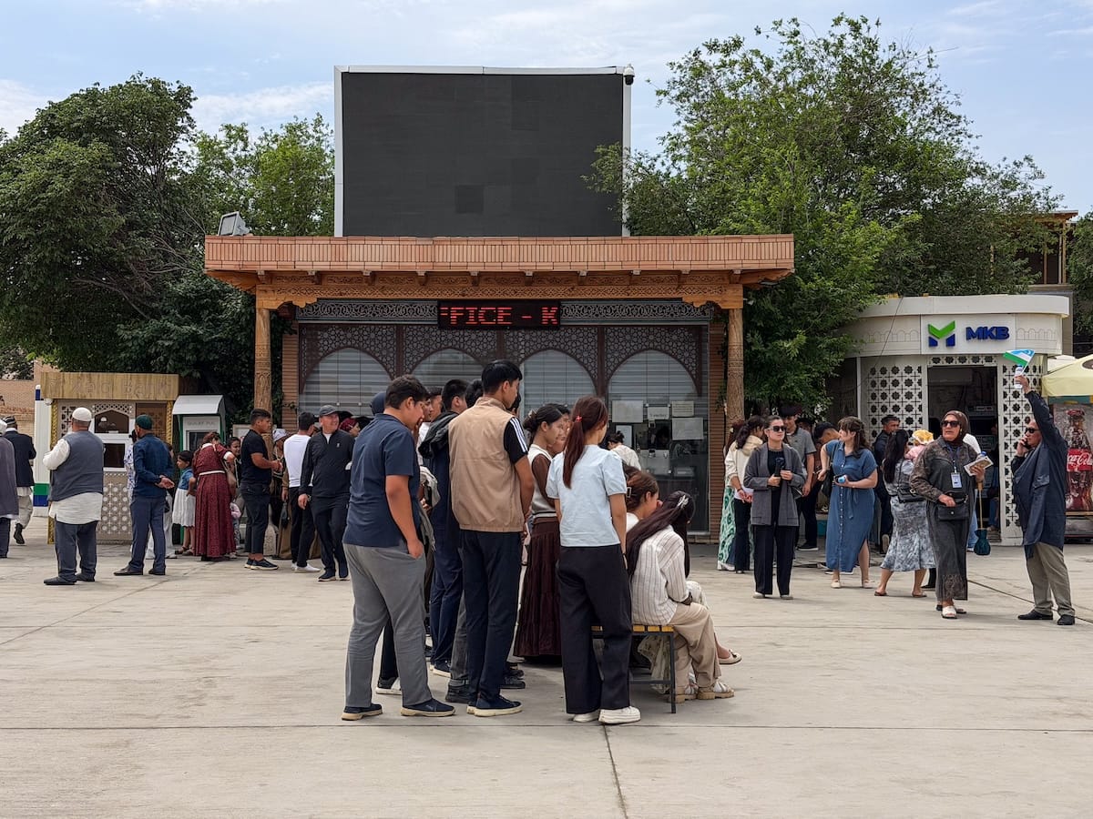 a mass of people outside a ticketing gate in khiva