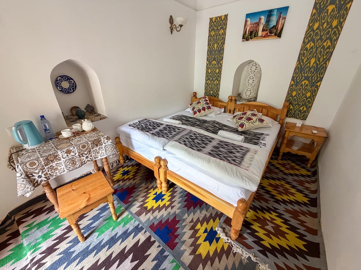 a room at a hotel that is a converted madrasah. has a bed, colorful carpet, and more