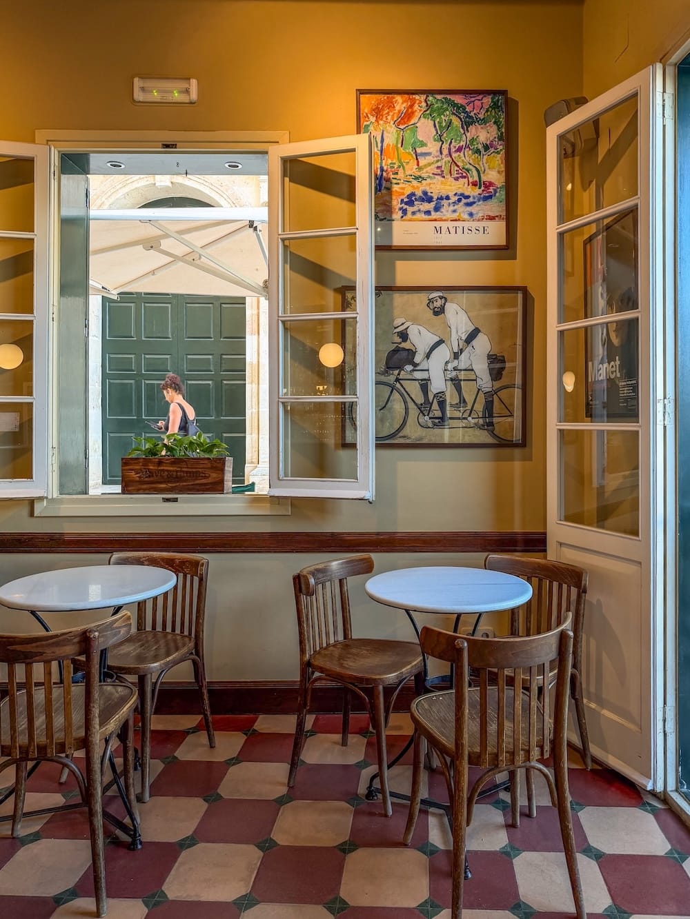 an old-fashioned cafe in spain with checkered floor, wooden stools, and photos on the wall