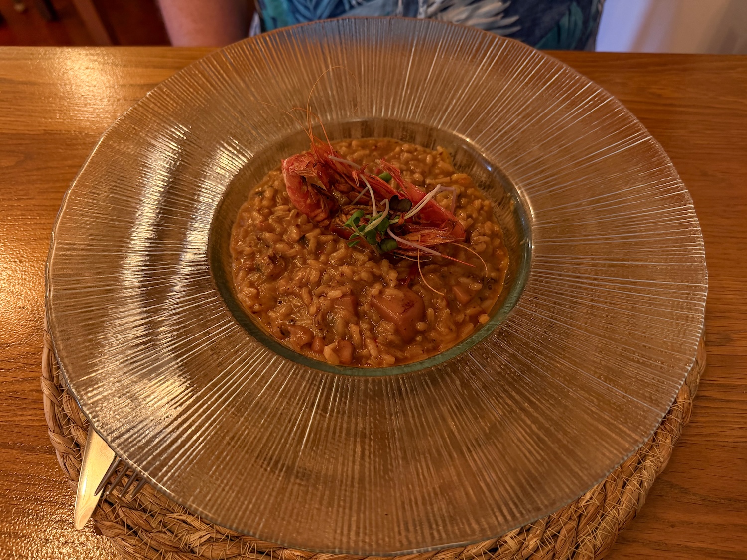 a clear dish of risotto with large prawns on top