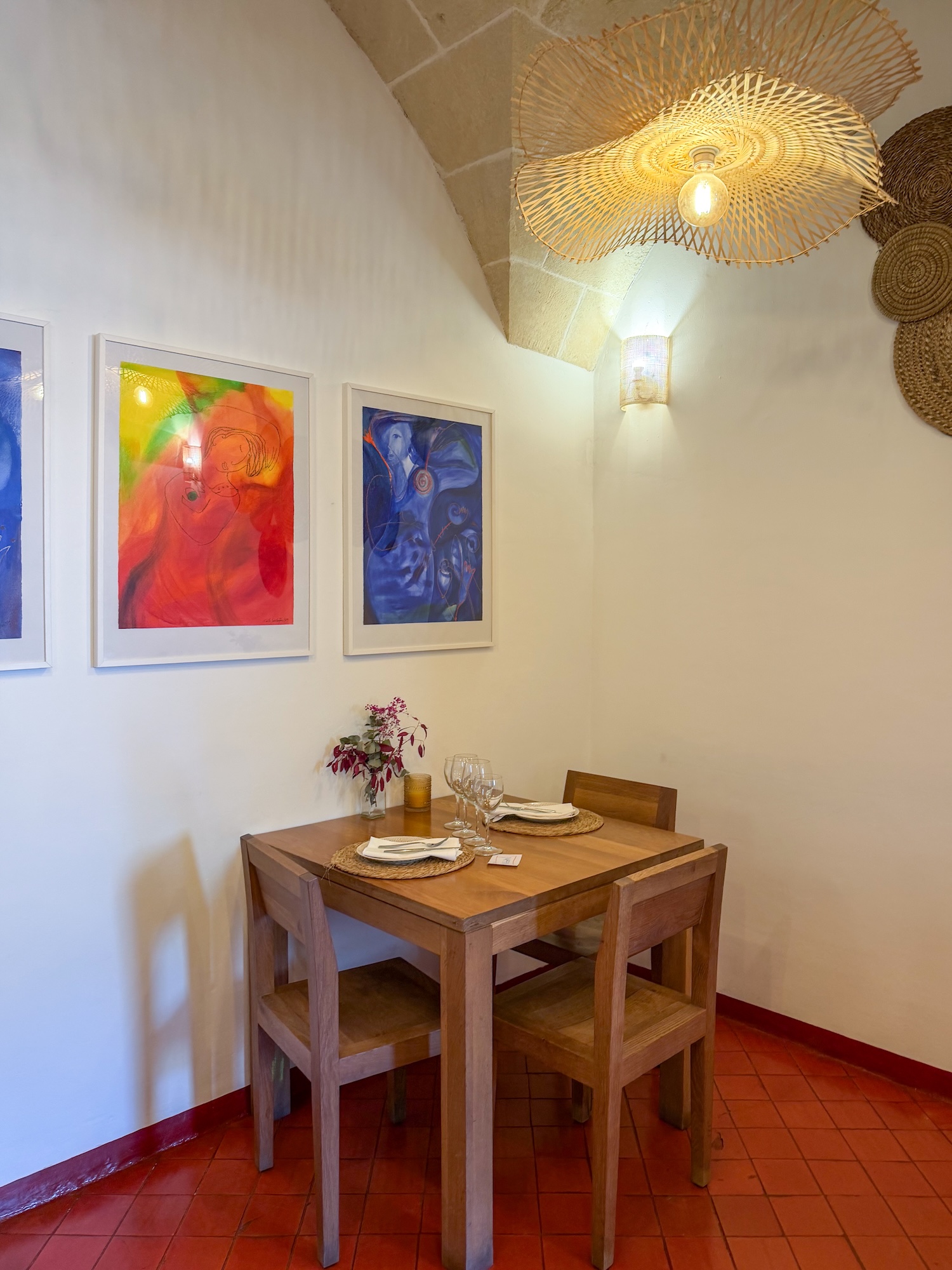 a minimalistic restaurant with a table in a corner and colorful paintings on the wall