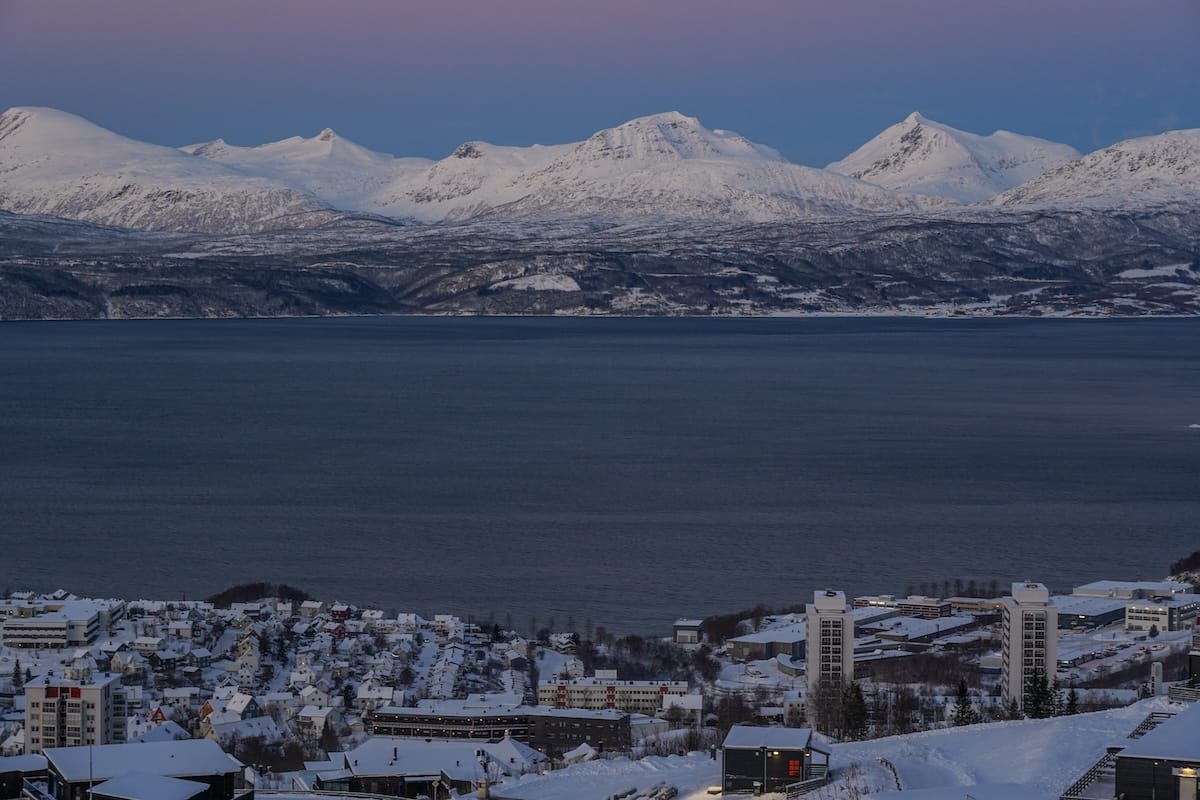 a Norwegian city overlooking a fjord with purple and pink skies