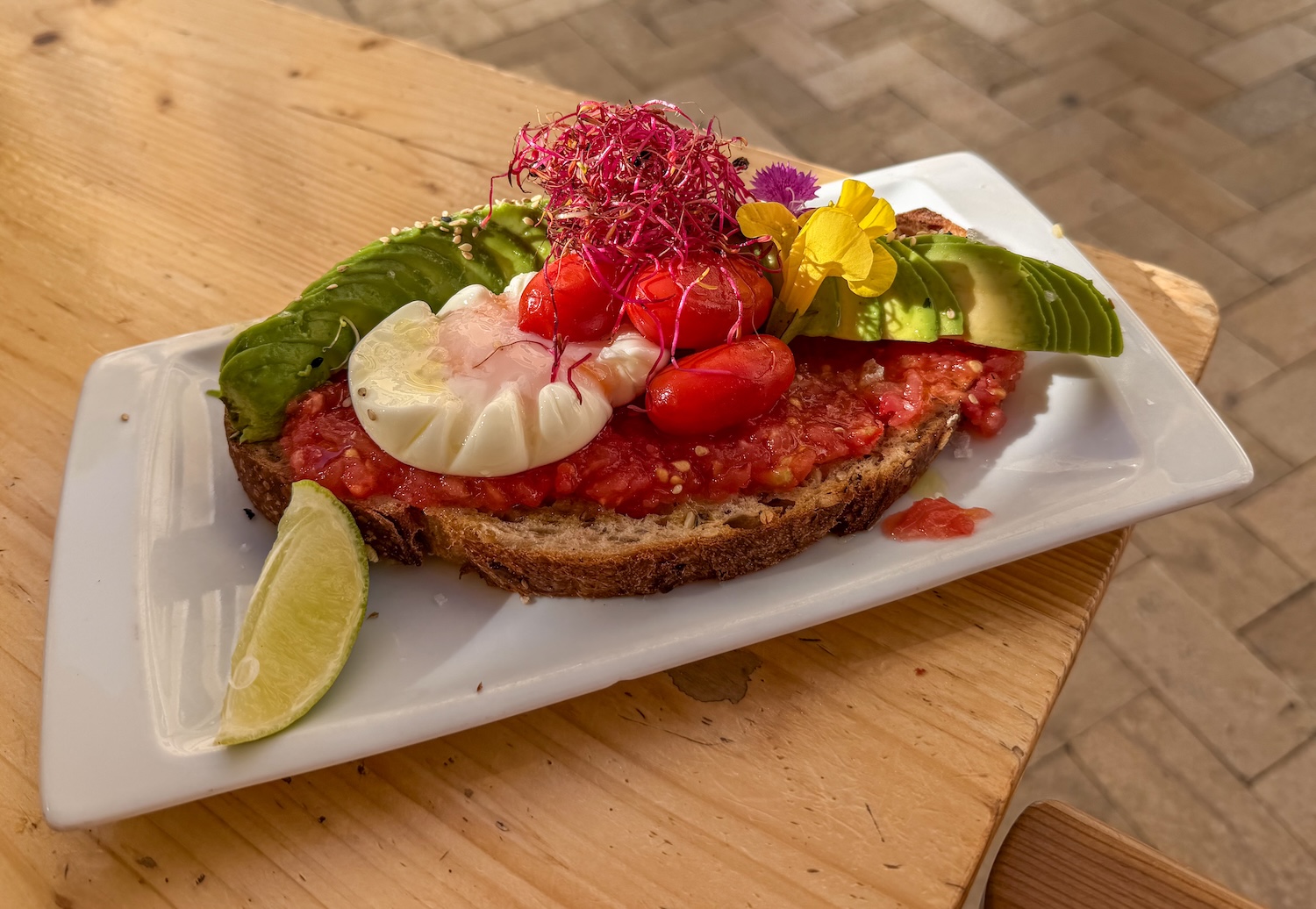 a plate with bread, tomatoes, a poached egg, and avocado on it