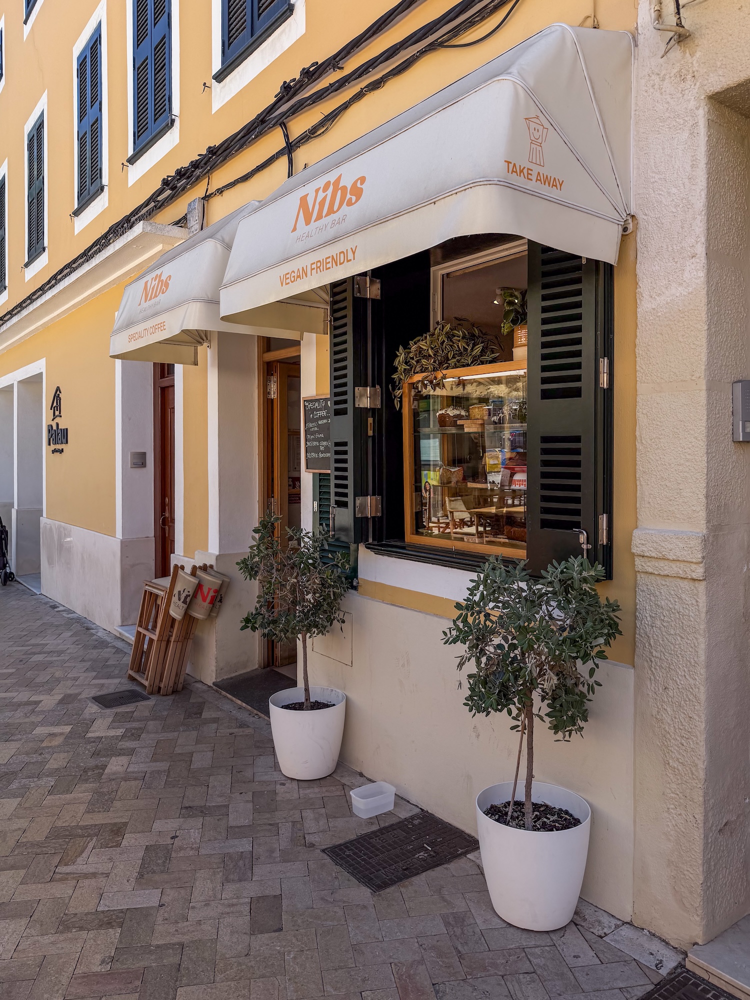 a photo of a cafe with plants on both sides of the window from the outside