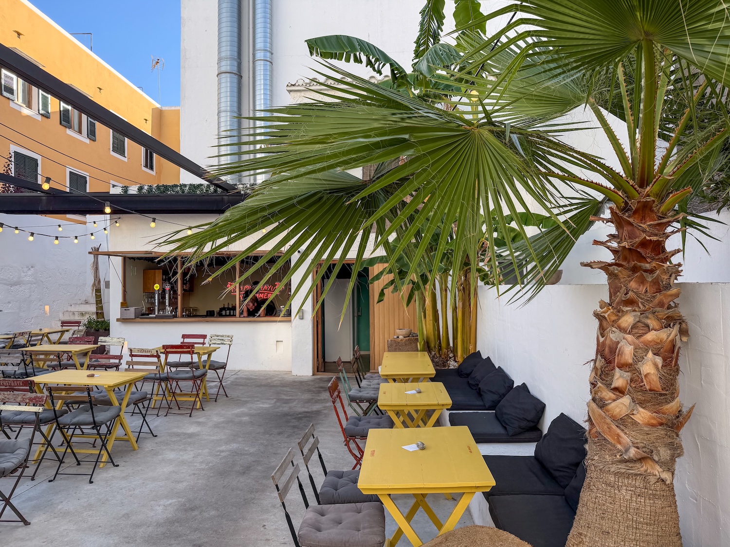 A guide to my favorite restaurants in Ciutadella, Menorca an outside terrace with many tables and a palm tree