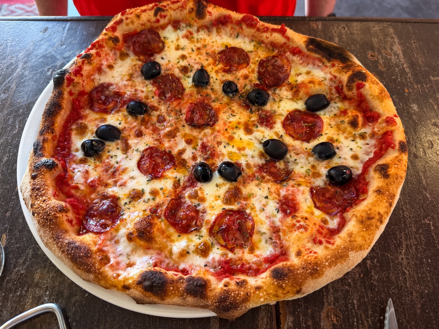 a large pizza with pepperoni and olives on a table