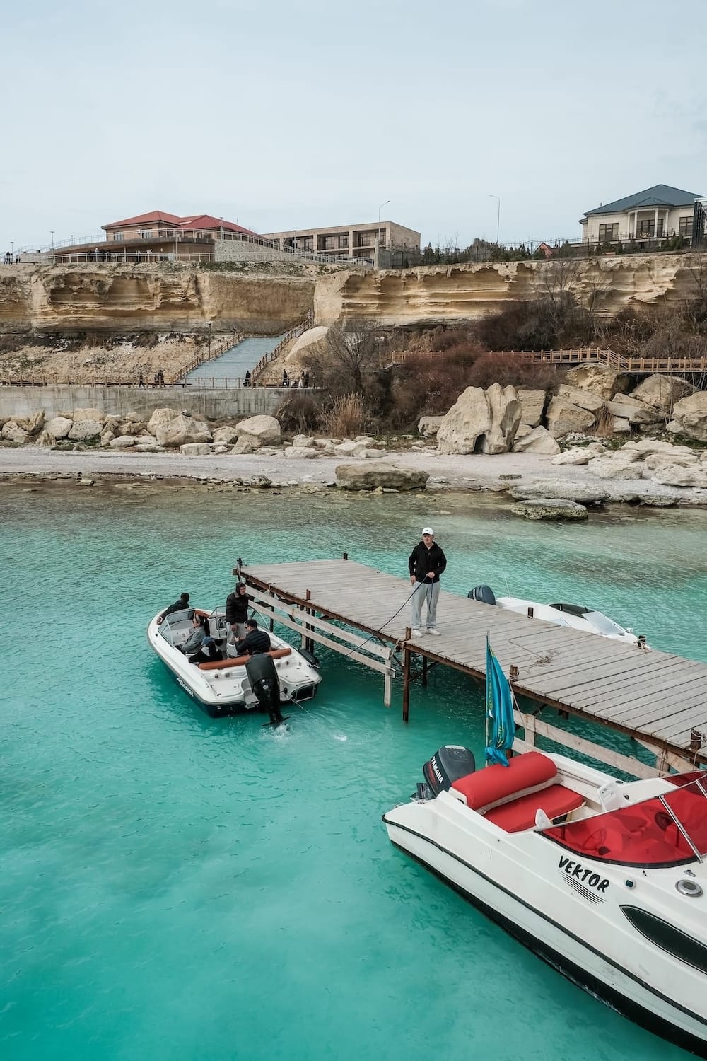 a photo of the blue/teal caspian sea and boats on a pier