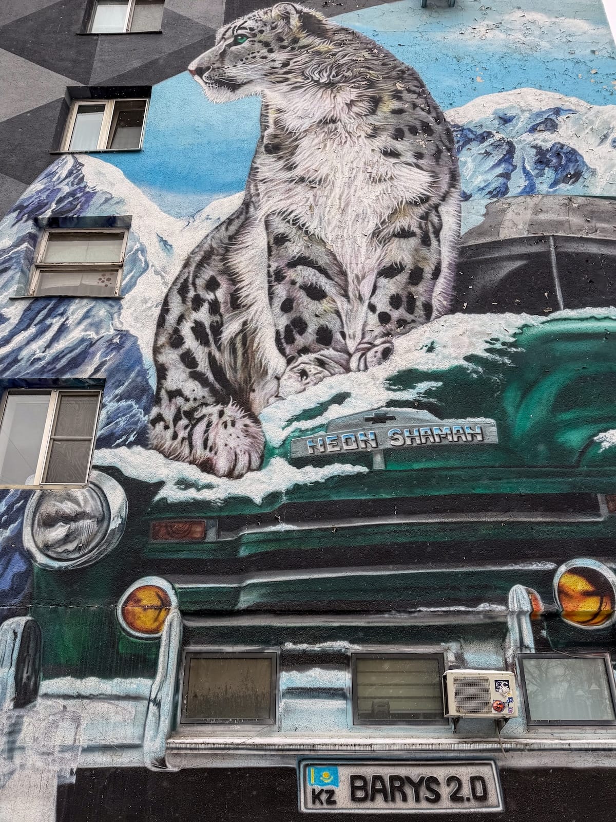 a mural on a building of a snow leopard on top of a car