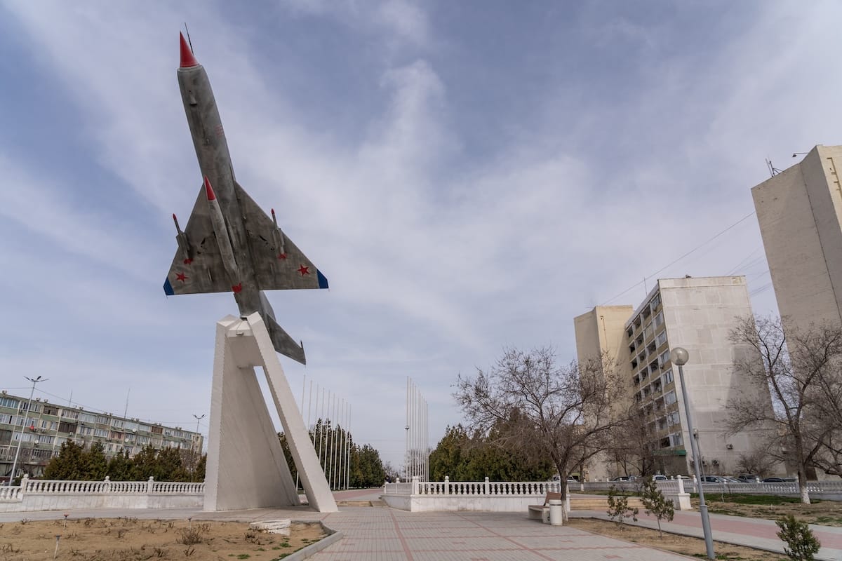 a MiG-21 fighter jet in a square in a city