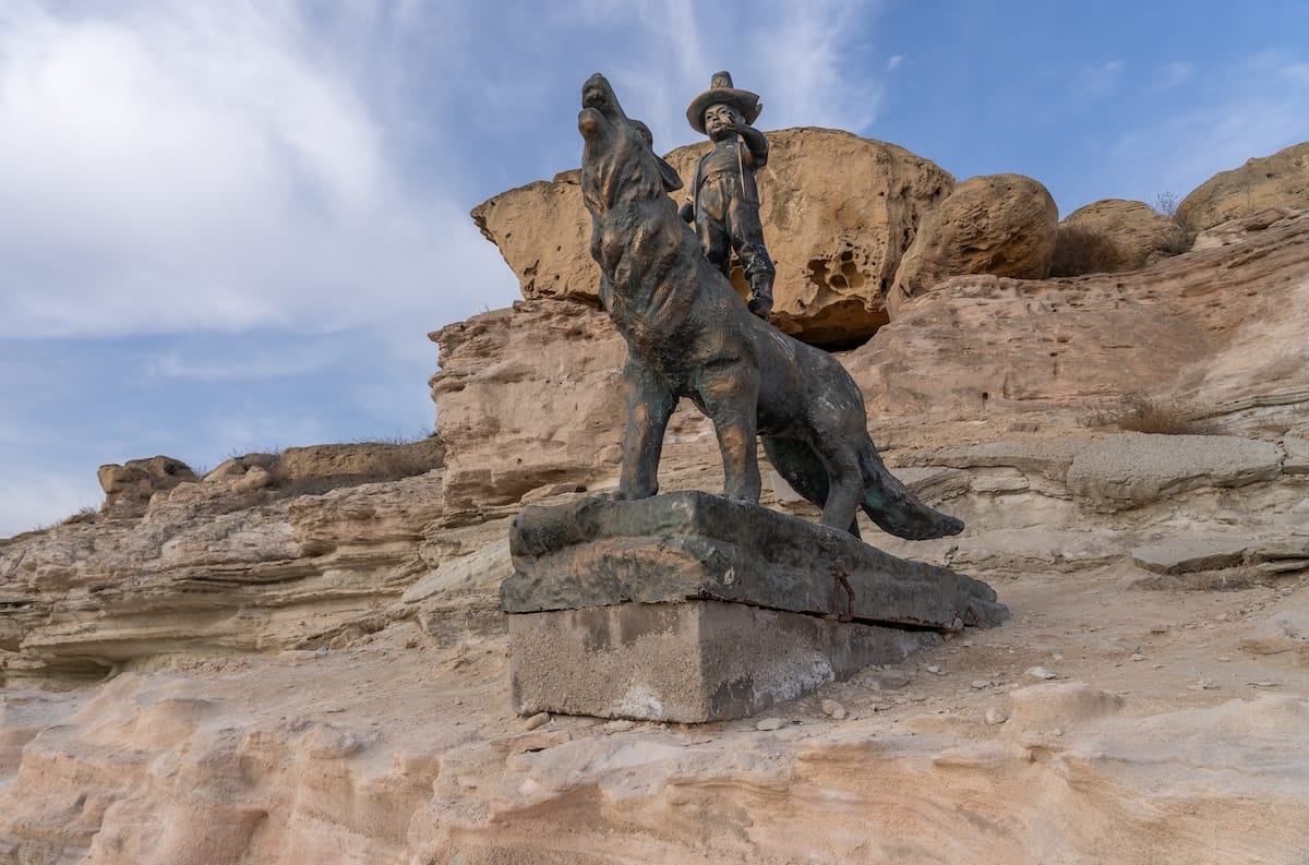 Best things to do in Aktau, Kazakhstan / travel guide a statue of a boy on a wolf by a tan rock