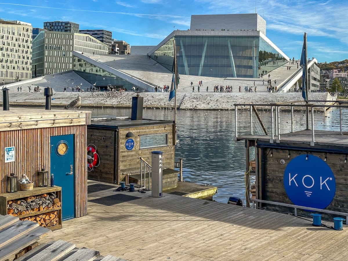 a fjord sauna in oslo norway with opera house behind it