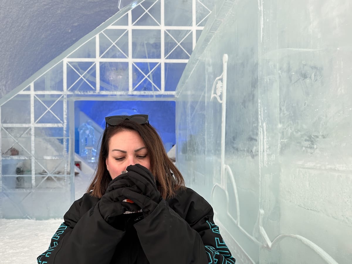 a woman having a drink in a large parka inside an ice bar in sweden