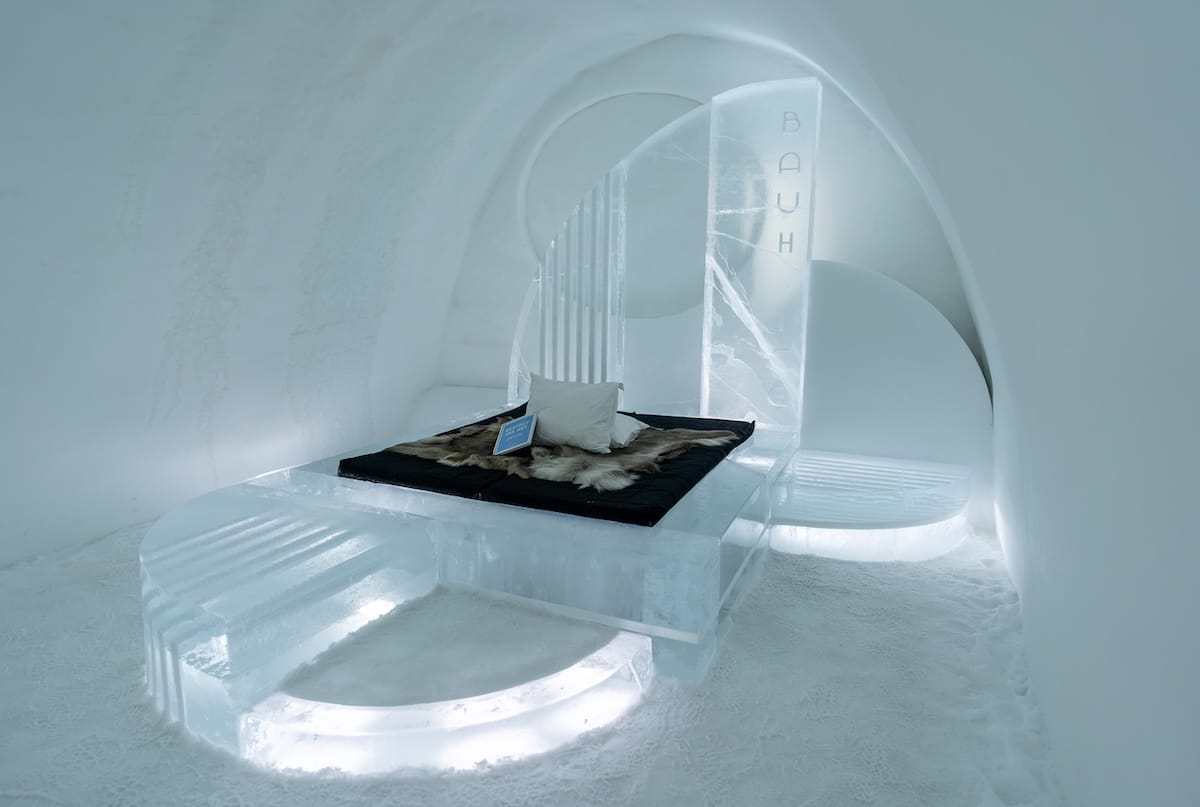 a room and bed made out of ice at an icehotel in sweden