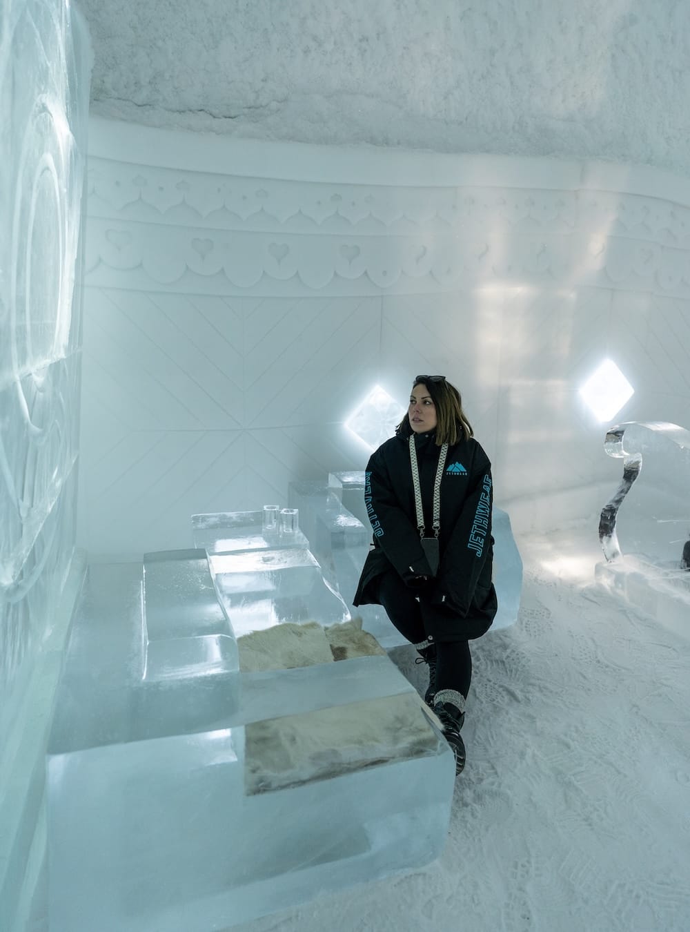 a woman sitting in a room made of ice in a hotel in sweden