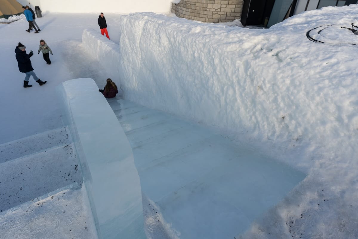 an ice slide at a snow park in sweden with kids going down it