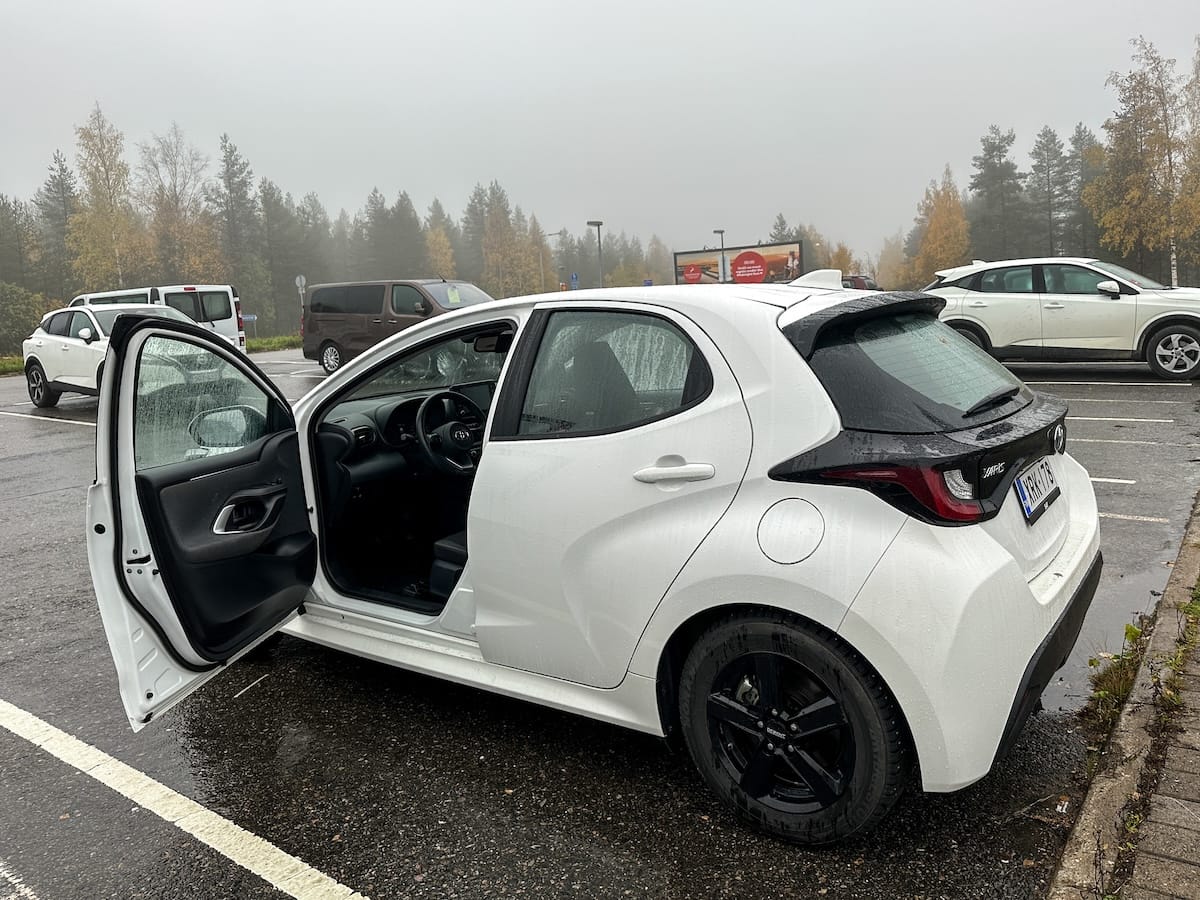 a white rental car with a door open in a foggy parking lot