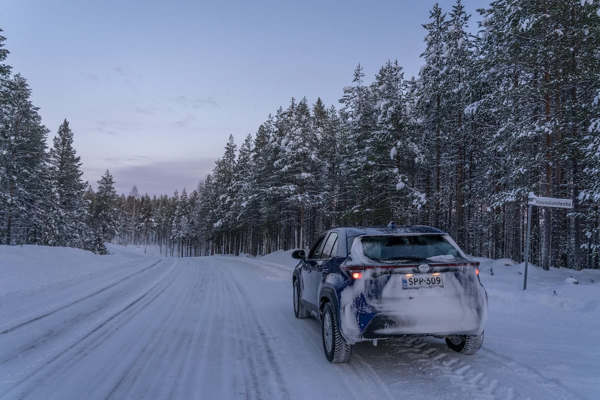 How to rent a car in Rovaniemi / a blue rental car on a snowy road under dark skies
