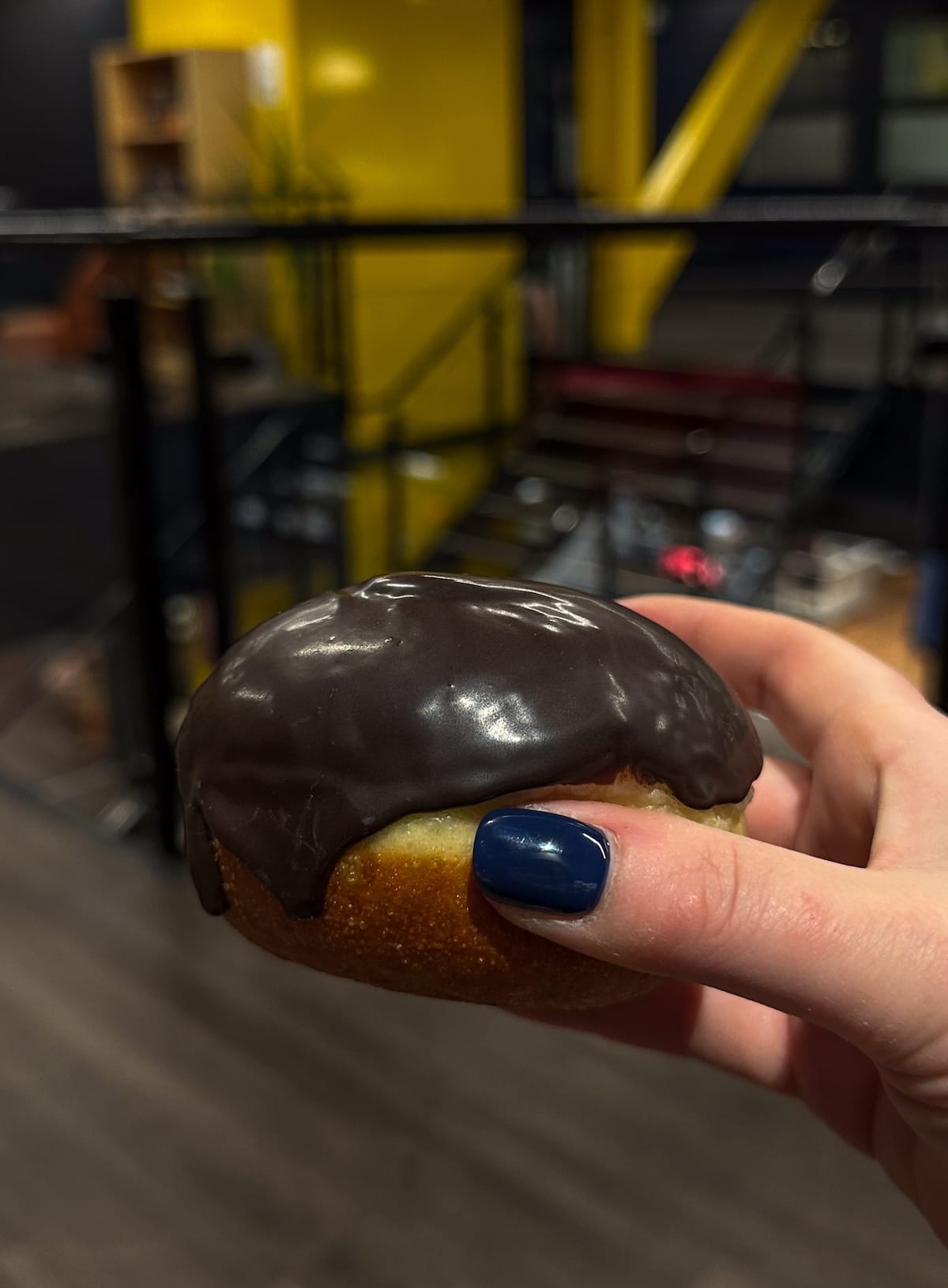 a woman's hand with a bun covered in chocolate in it