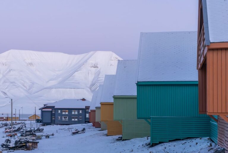 Svalbard in October travel guide colorful houses with snow-covered roofs and a snowy, treeless mountain in the background