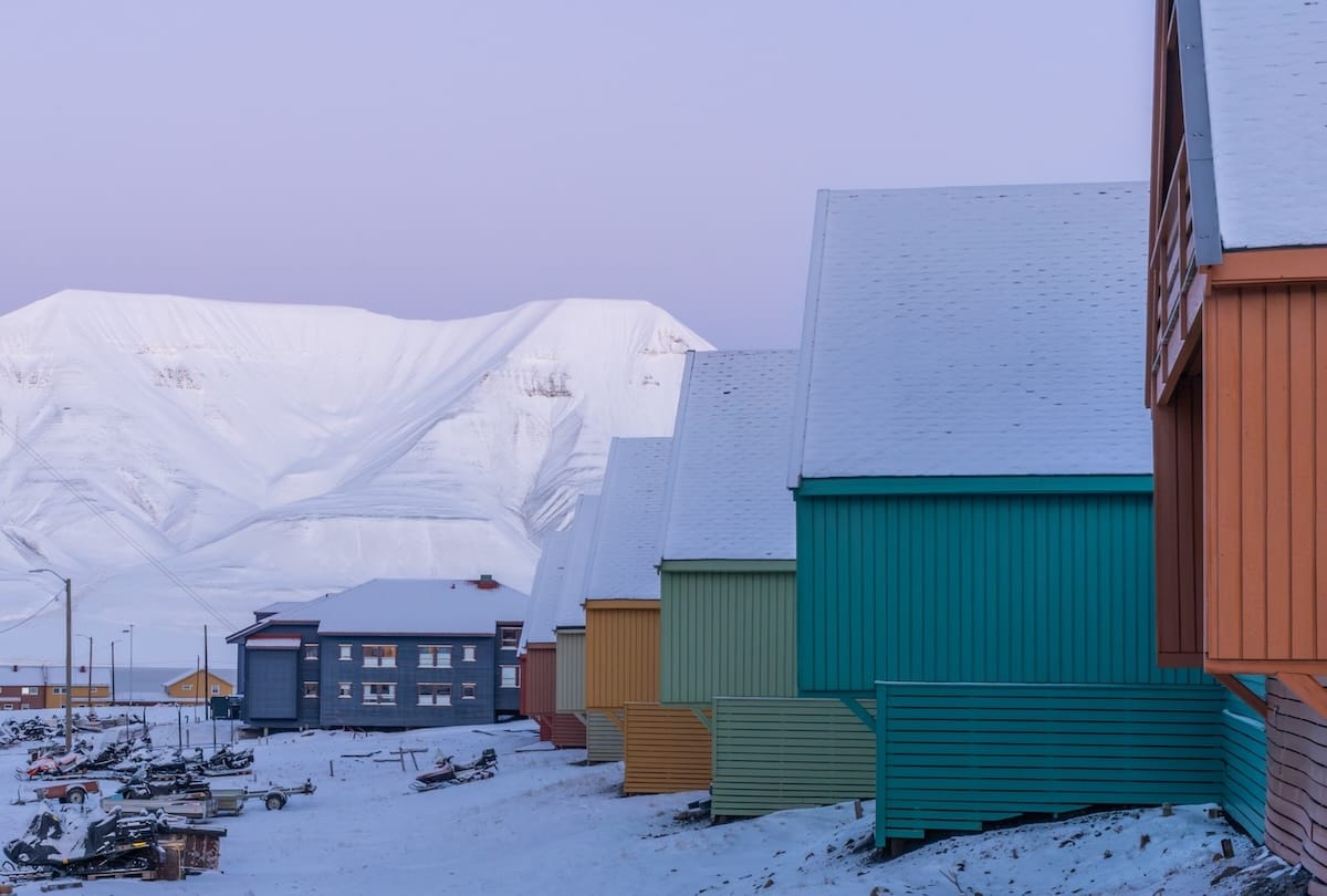 Svalbard in October travel guide colorful houses with snow-covered roofs and a snowy, treeless mountain in the background