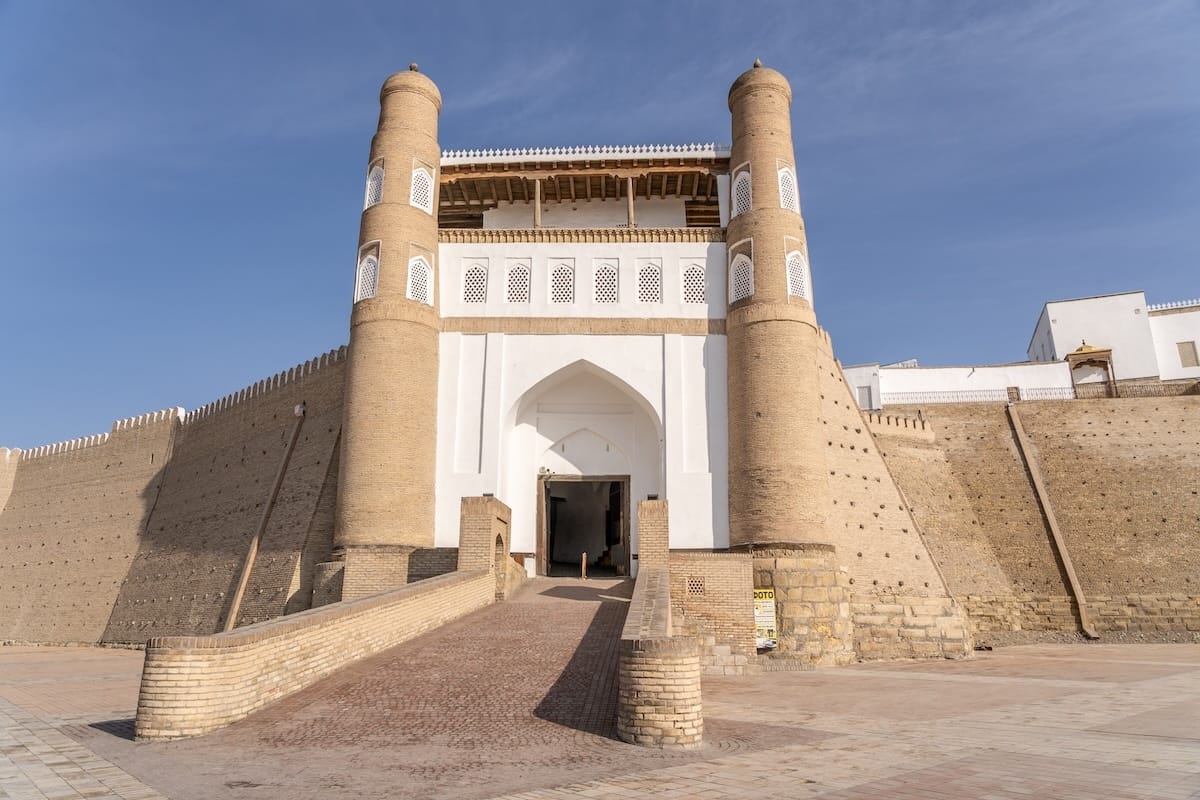 a photo of the Ark of Bukhara, a fortress-like structure with tan walls and a white entrance area