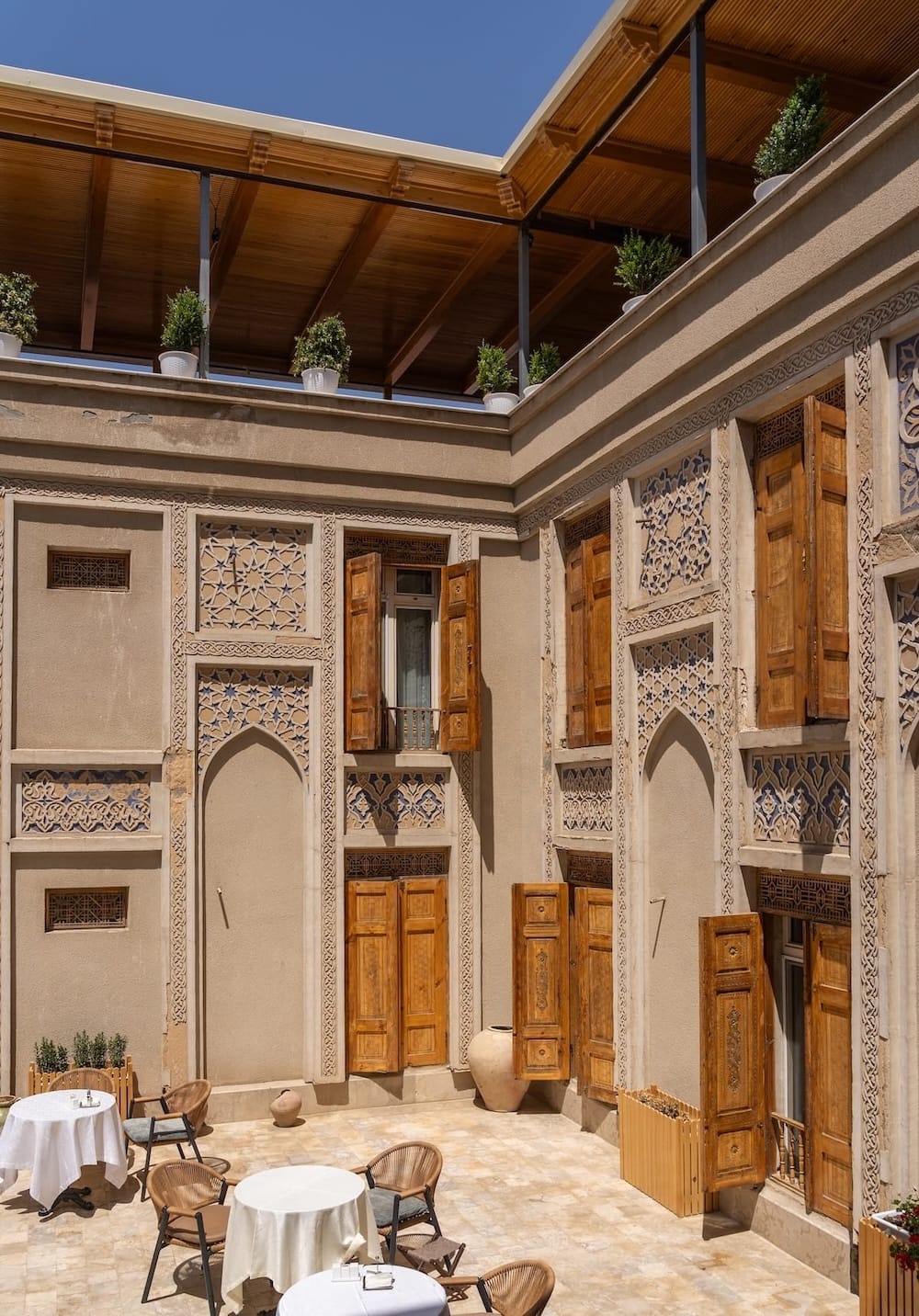 Ornate carved doorways and terrace seating at Ayvan Restaurant in Bukhara, Uzbekistan